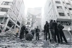  ?? AFP ?? LEFT People look at the rubble of a building in Gaza City that was destroyed by an Israeli air strike yesterday.