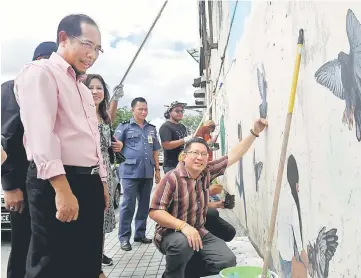  ??  ?? Wee (squatting) admiring a mural while Jumaini (left) and others look on.