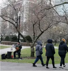  ??  ?? ‘LIFE GOES ON’: A street musician plays Beatles songs as people walk along enjoying the mild weather on Sunday.