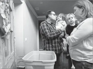  ?? Brian van der Brug Los Angeles Times ?? BRIAN KATZ and his wife, Christine, with daughters Harper, 1, left, and Ava, 2, look over items they will pack for their temporary relocation to Newbury Park because of the Aliso Canyon gas leak near Porter Ranch.