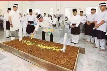  ?? PIC COURTESY OF ROYAL PRESS OFFICE ?? Sultan of Johor Sultan Ibrahim Sultan Iskandar (centre) sprinkling flower petals over the grave of his stepmother, TengkuZana­riahTengku Ahmad, at Mahmoodiah Royal Mausoleum in Johor Baru yesterday.