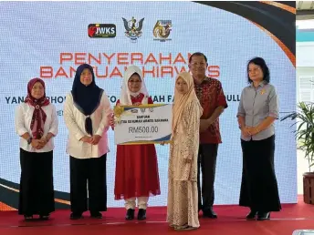  ?? ?? Fatimah (centre) presents a mock cheque for RM500 to the recipient of KIRWas, while others look on.