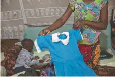  ?? Fezehai for The Washington Post — Malin ?? Elizabeth Auwa, 30, holds her daughter Monica’s school uniform.