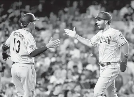  ?? Harry How Getty Images ?? MANNY MACHADO and Eric Hosmer celebrate at the plate after scoring the go-ahead runs in the sixth inning at Dodger Stadium.