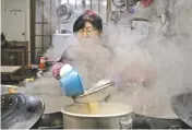  ??  ?? A woman cooks at a restaurant Monday in Gangneung, South Korea. Korean food is very different from what many foreign Olympians are used to eating.