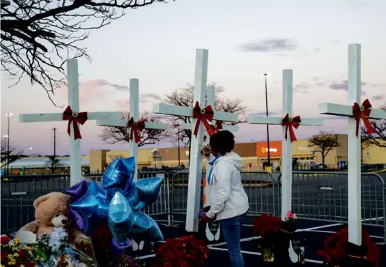  ?? JAHI CHIKWENDIU/WASHINGTON POST ?? Frances Shelton wrote a message on a cross outside the Walmart in Chesapeake, Va., after a mass shooting killed six of her coworkers there in November. A new fund to aid such victims, the first of its kind in the nation, was signed into law on Sept. 14.