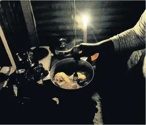  ?? /VELI NHLAPO ?? A woman prepares a meal on a primus stove during loadsheddi­ng by power parastatal Eskom in parts of Soweto.