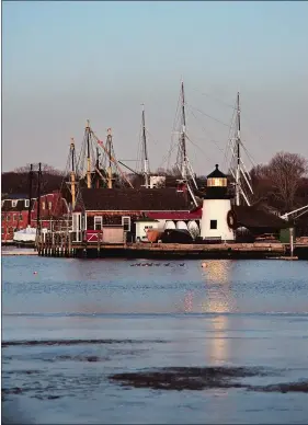  ?? SEAN D. ELLIOT/THE DAY ?? The replica of the 1901 Brant Point Light at Mystic Seaport casts its glow across the Mystic River at sunset on Thursday.