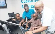  ??  ?? Cesley Baily, FLOW retail sales adviser (left), and Member of Parliament Julian Robinson show two participan­ts from the JA Biztown Tech Camp how to use a computer during a visit to a FLOW corporate store.