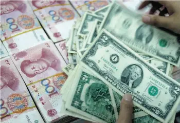  ?? ST R /A F P/G E T TY I M AG E S/ F I L E S ?? A bank teller counts stacks of U.S. dollars and Chinese yuan at a bank in Huaibei, China.