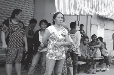  ?? BING GONZALES ?? RELATIVES wait for their loved ones who are trapped inside the collapsed three-story South Green Marketing in Padada, Davao del Sur following the earthquake on Sunday. At least three bodies have been retrieved from the building.