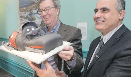  ??  WAYNE CUDDINGTON/OTTAWA CITIZEN ?? Mayor Jim Watson, with Councillor George Darouze, made his return to Ottawa city hall Monday following a snowmobile accident on Feb. 28 when he fractured his pelvis. He was presented with a cake in the shape of a snowmobile.