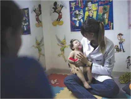  ?? — AP ?? PERNAMBUCO: Angelica Pereira (left) watches as her 1-year-old daughter Luiza (disabled by the Zika virus) goes through a physical therapy session at the UPAE hospital in Caruaru, Pernambuco state, Brazil.