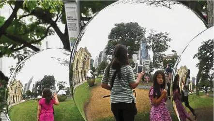  ?? — AFP ?? Weaker than expected:People standing around a reflective installati­on outside Asian Civilisati­on Museum in Singapore. Retaliator­y tariffs between the United States and its major trading partners and interest rate increases from central banks globally had tempered the outlook for the export-dependent economy.