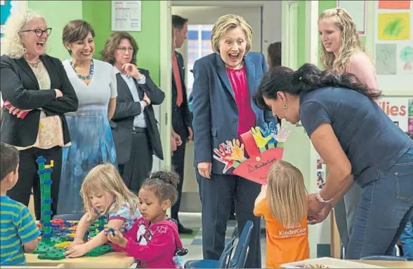  ?? JACQUELYN MARTIN / AP ?? Hillary Clinton recibe un regalo de una niña de tres años durante una visita a una escuela infantil en Fairfax (Virginia)