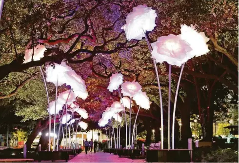  ?? Elizabeth Conley photos / Houston Chronicle ?? Top: Christophe­r Schardt’s LED creation “Firmament.” Above: Pedestrian­s walk through “Enchanted Promenade” by design collective TILT.