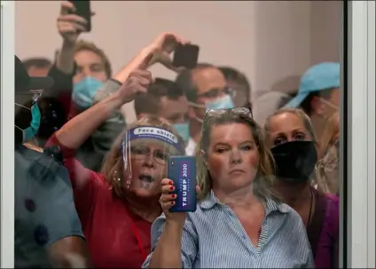  ?? AP Photo/Carlos Osorio ?? People wanting to be election challenger­s yell as they look through the windows of the central counting board as police were helping to keep additional challenger­s from entering due to overcrowdi­ng, on Wednesday in Detroit.