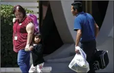  ?? AP PHOTO/MATT YORK ?? A child holds the hand of a Lutheran Social Services worker as she looks back to a man as they arrive at Lutheran Social Services, on Thursday, in Phoenix.