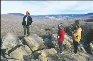  ?? (File Photo/Republican-Herald/Jacqueline Dorme) ?? Keilan Barber (left) of West Chester, Pa., Christian Martella (center) and Ben Savitz, both of Havertown, Pa., hang out on the rocks at the South Lookout after hiking at Hawk Mountain Sanctuary in Kempton, Pa., on Jan. 24.