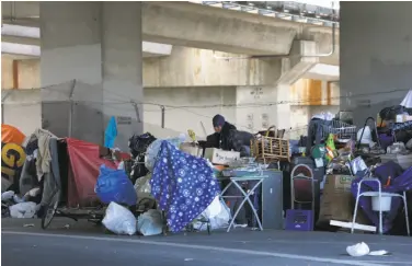  ?? Photos by Paul Chinn / The Chronicle ?? Above: A homeless encampment on Northgate Avenue below Interstate 980 in Oakland is jam-packed with the campers’ belongings and refuse.