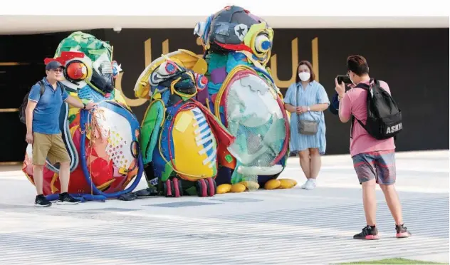  ?? Kamal Kassim/ Gulf Today ?? ↑
Visitors pose for a photograph with funky creatures made of recycled items at Expo 2020 Dubai on Saturday.