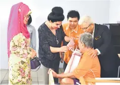  ??  ?? Raghad (second left) presents an ‘angpow’ to one of the residents while the (home) principal Dariel Thiong Yiew Seng (third left), state Welfare Department director Abang Shamsudin Abang Seruji (right) and Fatimah (left) look on.