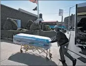  ?? MARK LENNIHAN/AP ?? William Samuels delivers caskets Friday to the Gerard Neufeld Funeral Home the pandemic in Queens, New York.