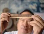  ??  ?? Leo Emmanuel Castro holding a piece of bamboo inscribed with indigenous Baybayin script at his shop in Manila.