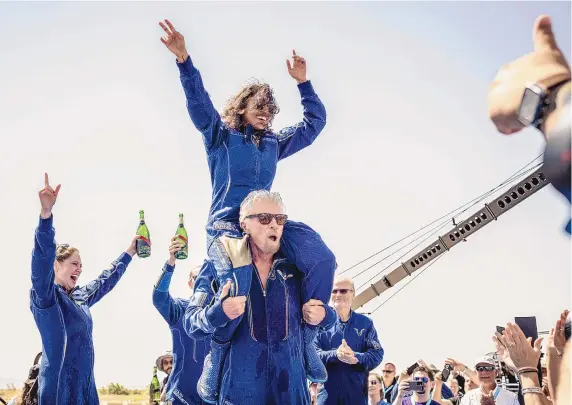  ?? ROBERTO E. ROSALES/JOURNAL ?? Virgin Galactic founder Sir Richard Branson carries Astronaut Sirisha Bandla, the company’s vice president of government affairs and research operations, on his shoulders while celebratin­g their successful spacefligh­t aboard VSS Unity at Spaceport America on Sunday. “As you go into space, the views are breathtaki­ng,” Branson said Sunday.