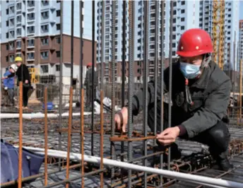  ??  ?? Huang Jiusheng, a constructi­on project manager, checks the spacing of steel bars on a constructi­on site in Xinzheng, Henan Province in central China, on March 12
