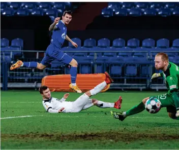  ?? FOTO: GUIDO KIRCHNER/DPA ?? Schalkes Stürmer Benito Raman erzielt gegen die Ulmer Thomas Geyer und Torwart Maximilian Reule das Tor zur 3:0-Führung.