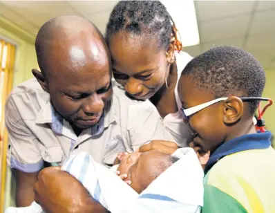  ?? PHOTOS BY RICARDO MAKYN/CHIEF PHOTO ?? Sinclair Hutton caresses his son, Sae’breon, alongside the child’s mother, Suzett Whyte, and brother, Rudean, at the Denham Town Police Station minutes after he was returned to his family by the Child Protection and Family Services Agency yesterday. EDITOR