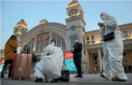  ?? AP ?? Passengers wearing protective suits to protect against the spread of new coronaviru­s gather outside of Hankou train station ahead of the resumption of train services in Wuhan in central China’s Hubei Province.