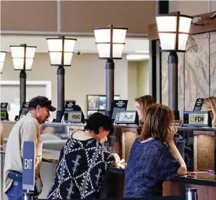  ?? Michael Wyke ?? Customers conduct their business at the teller windows of the First Liberty National Bank in Liberty, northeast of Houston.