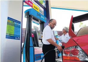  ?? SOMCHAI POOMLARD ?? A motorist uses a self-serve pump on Srinakarin Road. Local retail fuel prices have fallen during the last six months in accordance with the global market.