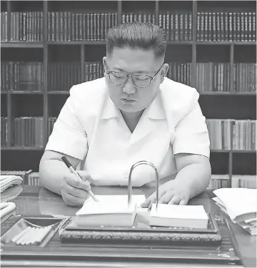  ?? AFP/ GETTY IMAGES ?? North Korean leader Kim Jong Un signs documents for the test launch of an interconti­nental ballistic missile. He is the third generation of his family to rule the isolated country.