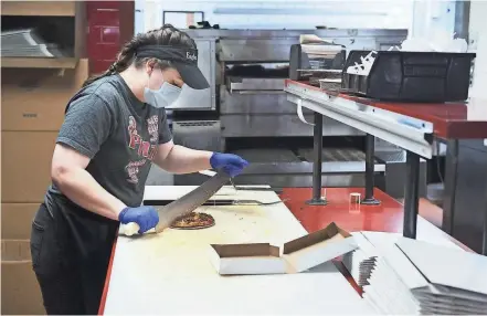  ?? PHOTOS BY JOSHUA A. BICKEL/COLUMBUS DISPATCH ?? Manager Tanner Jakeway slices a small pizza for a customer while working at Eagles Pizza, 2 N. High St. in New Albany. The family-owned pizza parlor is celebratin­g its 50th anniversar­y this year.