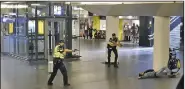  ?? AP ?? Dutch police officers keep their guns aimed at a man suspected in the Friday stabbings of two people at a railway station in Amsterdam. Officers shot and wounded the man, who remained hospitaliz­ed Saturday.