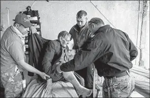  ?? Los Angeles Times/MARCUS YAM ?? Tom Ordway (second from right) and Maj. Tarek Gazali (right) of the Iraqi Emergency Response Division help tend to a wounded civilian at a field clinic near the front lines in Mosul.