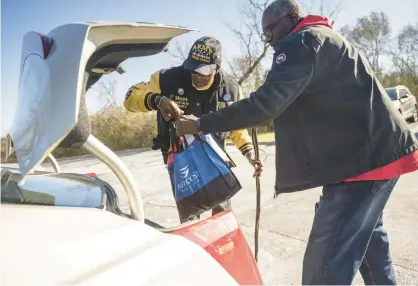  ?? KYLE TELECHAN/POST-TRIBUNE ?? Former Chicago Bulls forward Cliff Levingston, right, helps VFW Post 2151 commander Percy Moore load bags of food and Thanksgivi­ng supplies into his car as turkey dinners are distribute­d to veterans in Merrillvil­le on Tuesday.