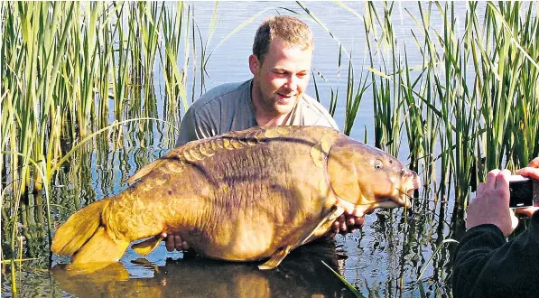  ??  ?? Brian Mandry, an angler, with Two Tone at Conningbro­ok Lake in Kent. He was the last person to catch the monster carp before its death five years ago. Below: anglers gathered to mourn the fish’s passing