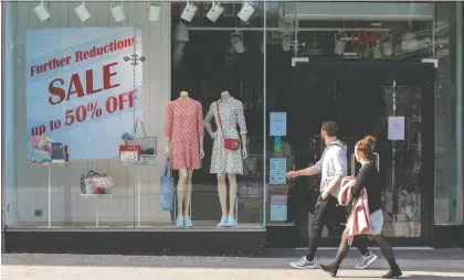  ?? PAUL FAITH/AFP/GETTY IMAGES ?? People walk past a temporaril­y closed-down clothes store in Dublin, Ireland, on Wednesday. While some try to get a bit of fresh air during the pandemic, behind closed doors day traders are struggling online just to complete a single transactio­n.