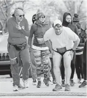  ?? [PHOTO BY NATE BILLINGS, THE OKLAHOMAN] ?? Runners shield themselves from the cold as they wait to start the YWCA Fearless K.