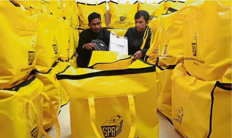  ?? — ZHAFARAN NASIB/ The Star ?? Good to go: Two Penang Election Commission (EC) officers – Muhammad Faheem Dul Fatthah (left) and Aiman Azeem Abdul Wahab – conducting final checks at the EC office in George Town.