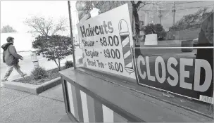  ?? ASSOCIATED PRESS FILE PHOTO ?? A woman walks past a closed barbershop in Cleveland in May. Data from the government’s coronaviru­s relief program for small businesses shows many minority-owned companies were kept waiting for loans even as they struggled through the pandemic.