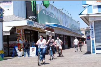  ?? WAYNE PARRY - THE ASSOCIATED PRESS ?? Bicyclists ride on the boardwalk in Seaside Heights, N.J. on May 15on the first day it opened during the coronaviru­s outbreak.