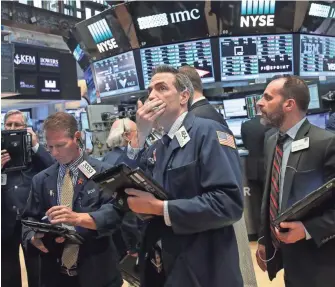  ?? DREW ANGERER, GETTY IMAGES ?? Anxious traders work on the floor of the New York Stock Exchange on Monday.