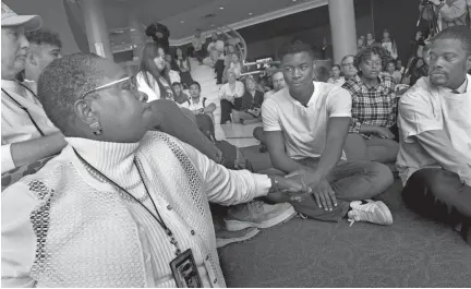  ?? Associated Press ?? ■ Aura Wharton-Beck, left, an assistant professor at the University of St. Thomas, clasps hands with Kevyn Perkins, center, Oct. 25 during a moment of silence before a protest at the university.