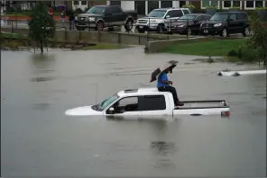  ?? AP/Houston Chronicle/MELISSA PHILLIP ?? A man sits atop a truck Thursday on a flooded road in Houston.