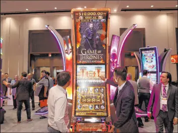  ??  ?? Ryan Scott with Aristocrat Technologi­es, right, shows Clint Koehn of Newcastle, Okla., the “Game of Thrones” slot machine at the Aristocrat gaming booth.